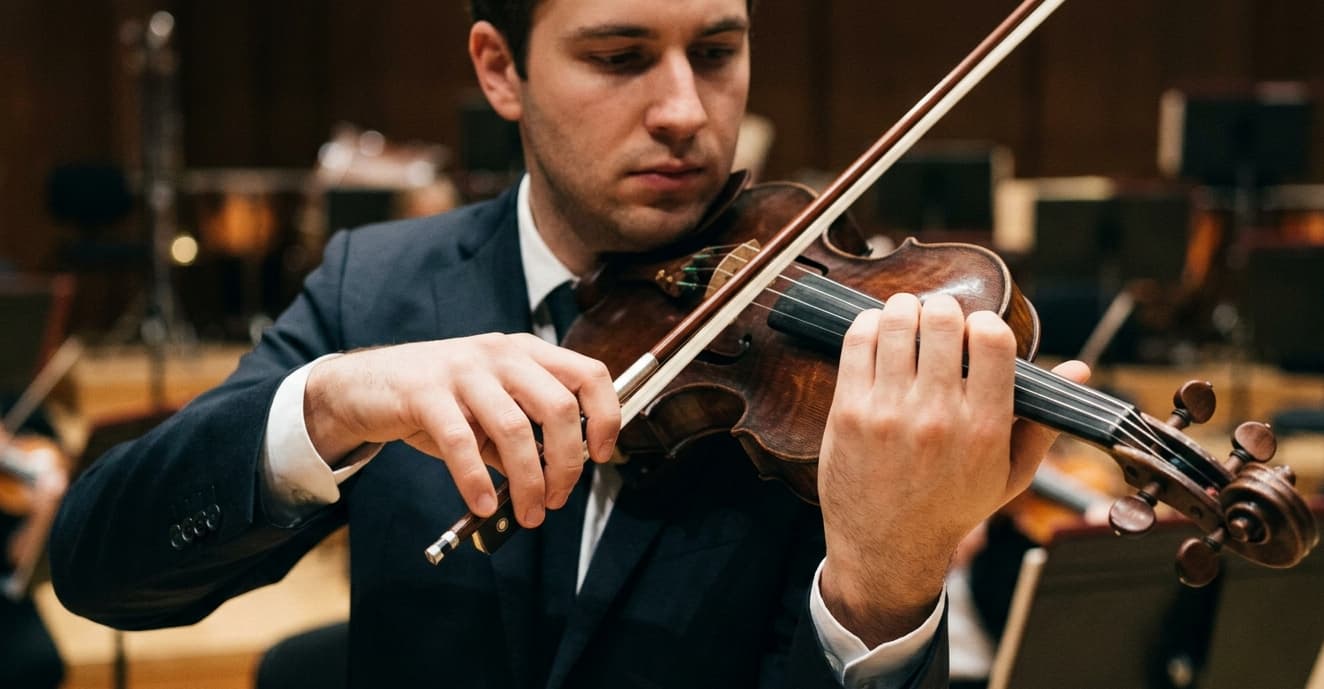 Close view of a violinist’s right arm and bow hand during a performance